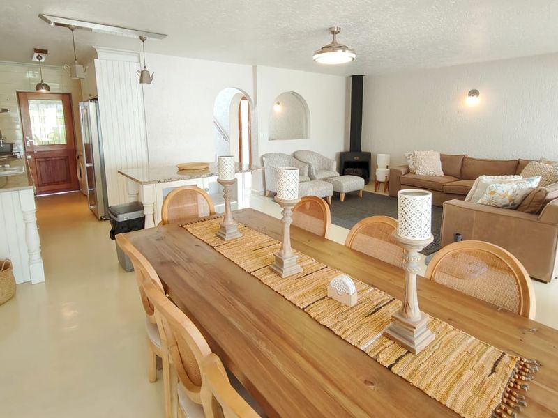 Spacious open-plan living, dining, and kitchen area featuring a freestanding fireplace, arched architectural details, and neutral tiled flooring throughout.