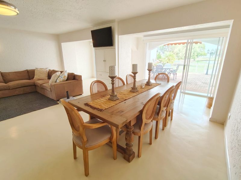 Spacious open-plan living and dining area featuring neutral flooring, built-in cabinetry, and large sliding glass doors providing seamless access to the outdoor patio.