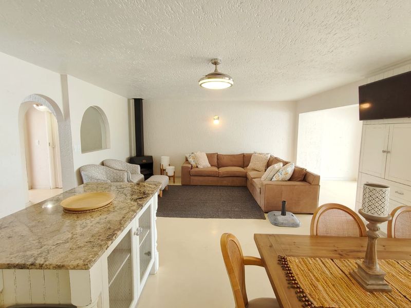 Spacious open-plan living area featuring a granite-topped kitchen island, a cozy fireplace, and distinctive arched architectural details connecting to adjacent spaces.