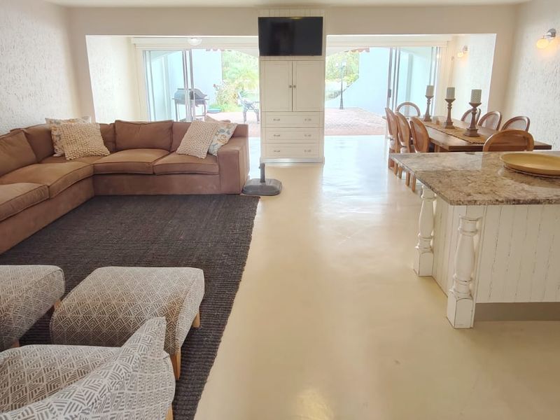 Spacious open-plan living and dining area featuring a central kitchen island with granite countertops and large sliding doors leading to the outdoor patio.