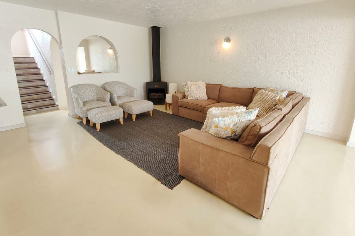 Spacious living room featuring a freestanding fireplace, polished concrete floors, and an arched architectural opening leading to the staircase.