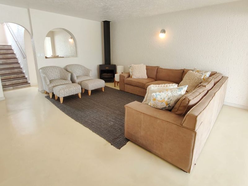 Spacious living room featuring a freestanding fireplace, polished concrete floors, and an arched architectural opening leading to the staircase.