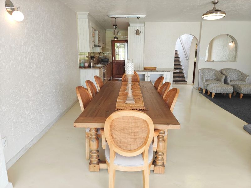 Spacious open-plan dining and kitchen area featuring neutral finishes, arched architectural details, and a staircase leading to the upper level.