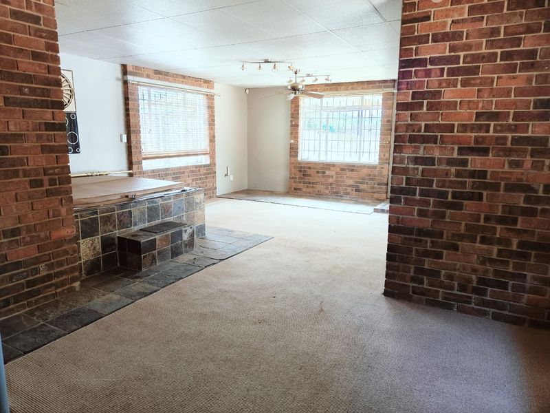 Spacious living area featuring exposed brick walls, a built-in tiled spa surround, and large windows with security bars.