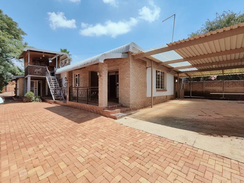 Front exterior view featuring a brick-paved driveway, covered carport, and an external staircase leading to an upper level.