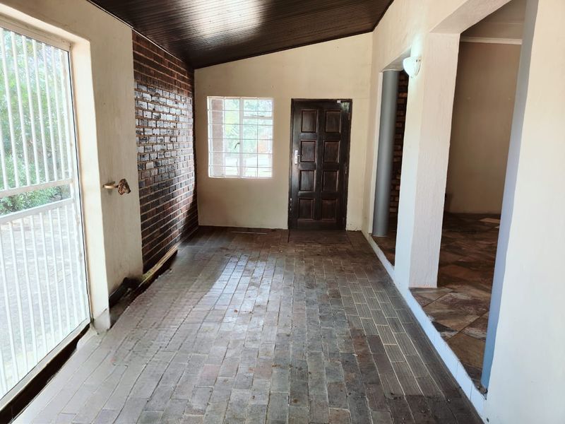 A covered patio area featuring brick flooring, an exposed brick feature wall, and a timber ceiling, providing a functional outdoor transition space.