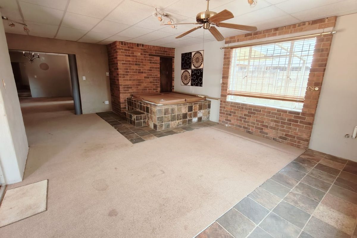 Spacious living area featuring a built-in indoor jacuzzi, exposed brick accents, and a combination of carpet and tile flooring.
