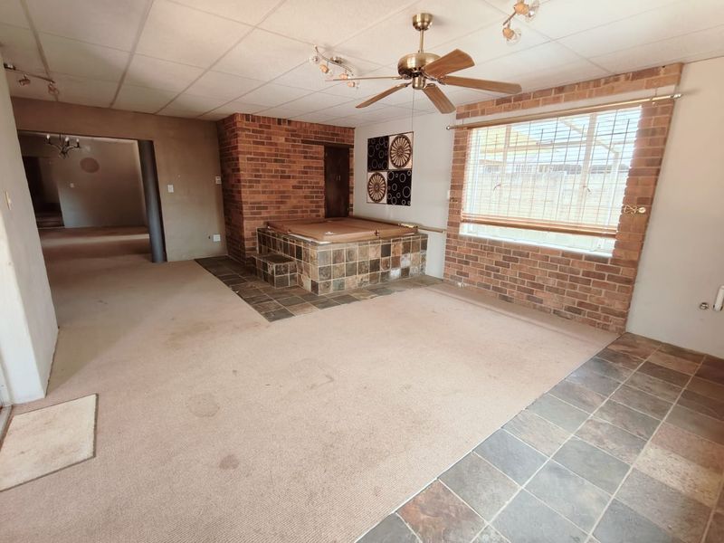 Spacious living area featuring a built-in indoor jacuzzi, exposed brick accents, and a combination of carpet and tile flooring.