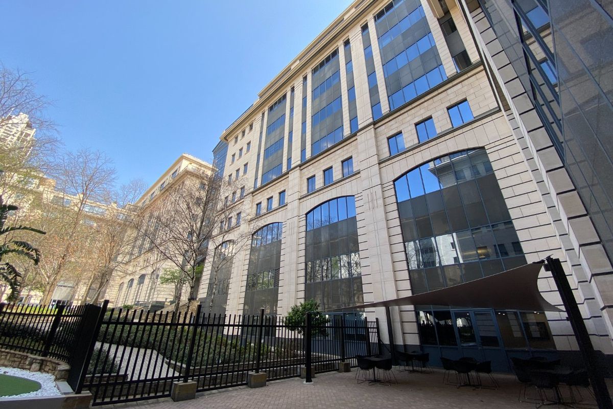 A view of the commercial building's rear facade featuring stone cladding, large glass windows, and a paved outdoor courtyard area with shade sail.