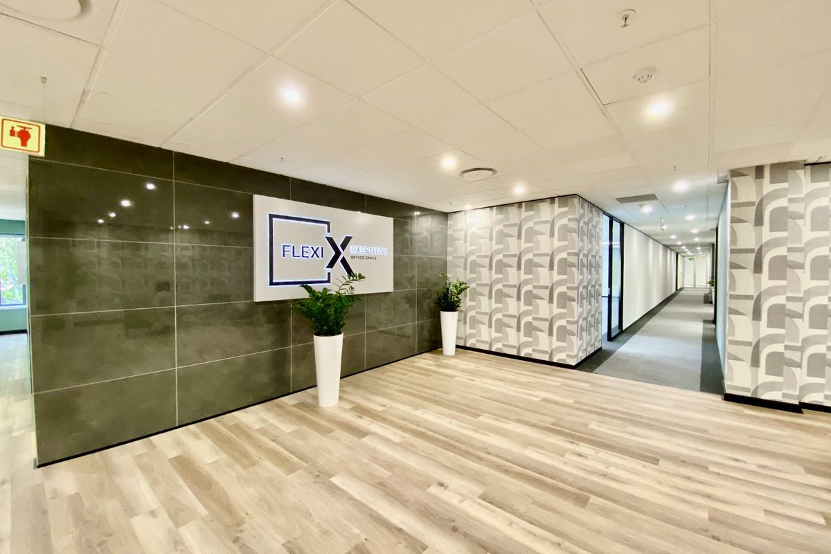 Modern commercial office entrance lobby featuring a tiled feature wall, patterned wallpaper accents, and wood-look flooring with recessed ceiling lighting.