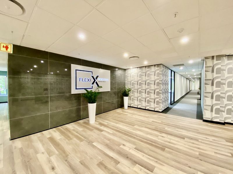 Modern commercial office entrance lobby featuring a tiled feature wall, patterned wallpaper accents, and wood-look flooring with recessed ceiling lighting.