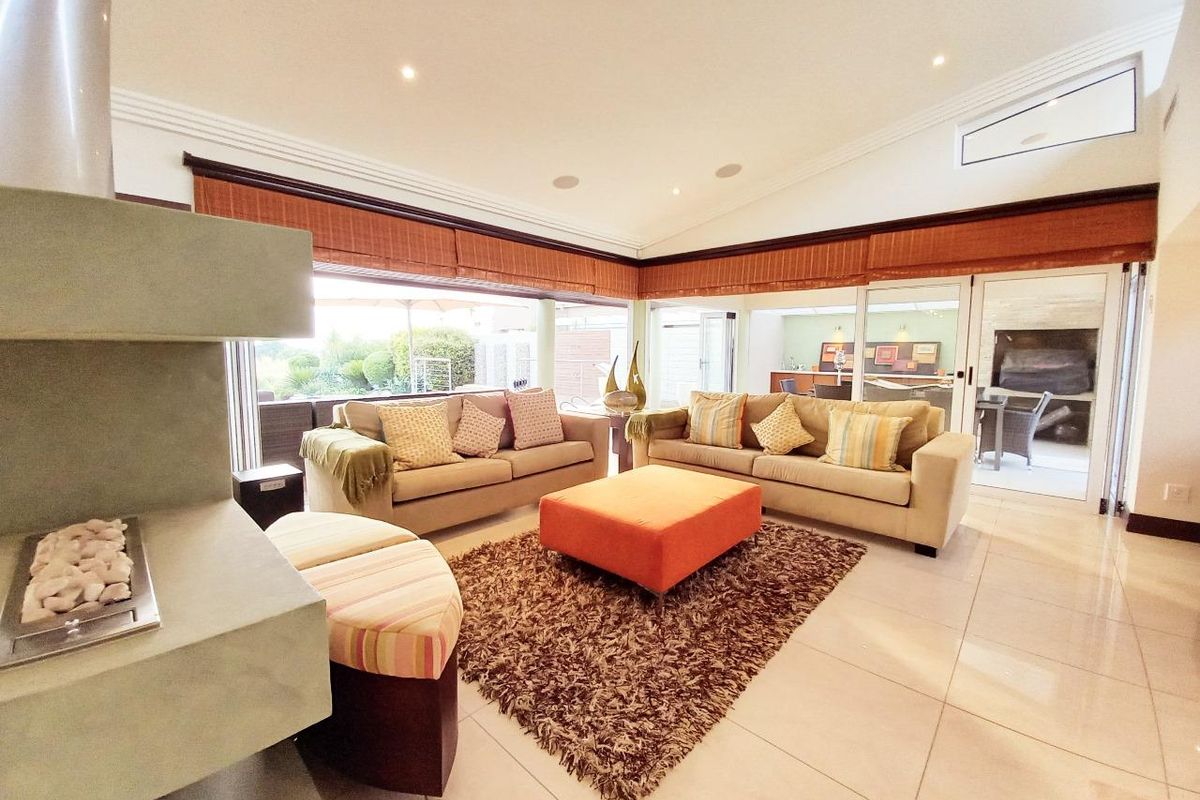 Spacious living room featuring a modern fireplace, vaulted ceilings, recessed lighting, and large sliding glass doors that provide seamless access to the outdoor patio area.
