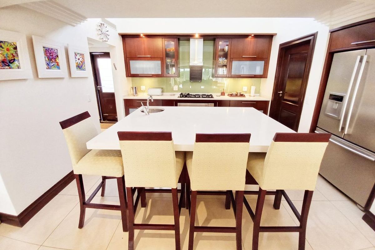 Modern kitchen featuring a large central island with stone countertops, dark wood cabinetry, gas hob, and integrated extractor fan.