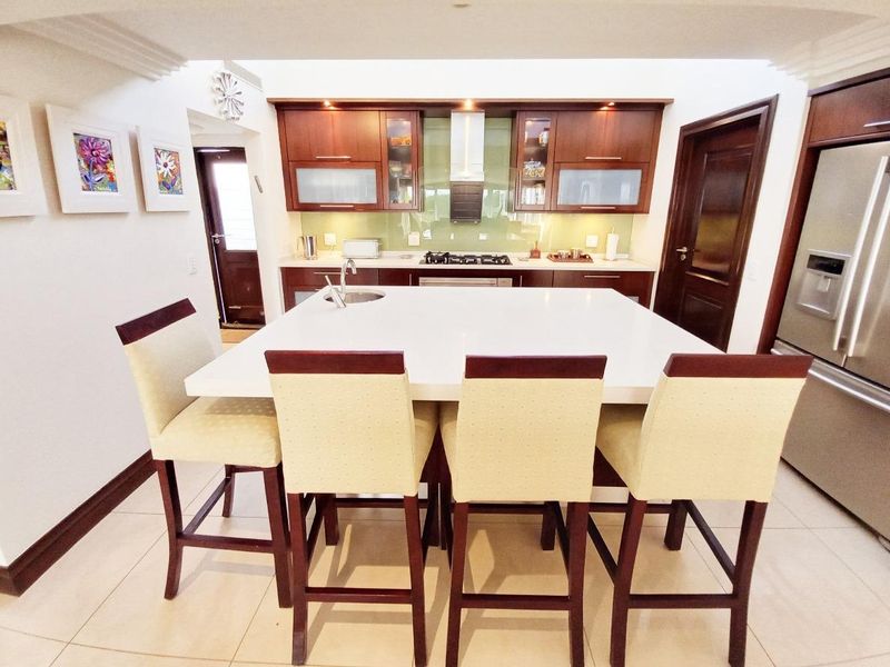 Modern kitchen featuring a large central island with stone countertops, dark wood cabinetry, gas hob, and integrated extractor fan.