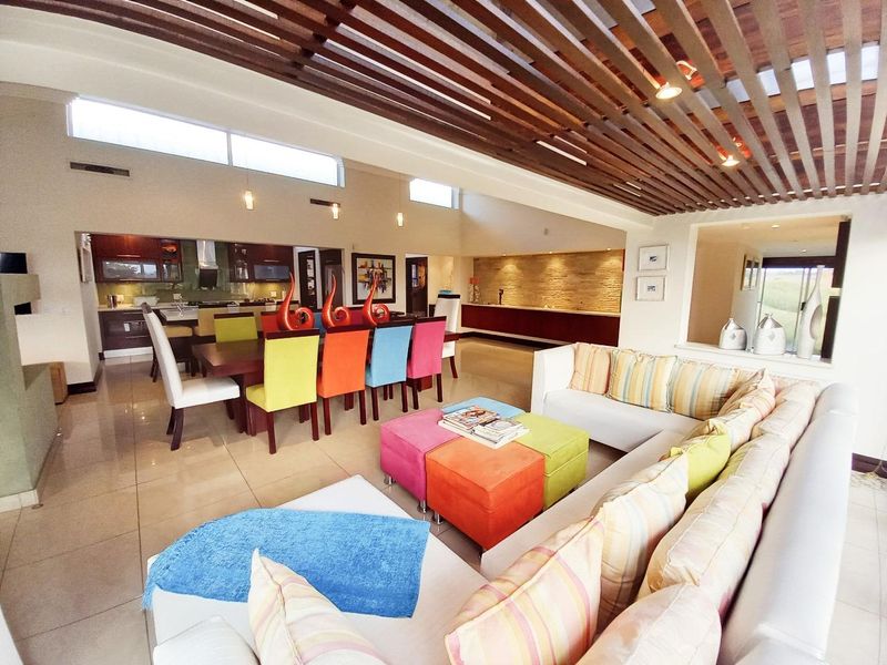 Spacious open-plan living and dining area featuring a striking timber slat ceiling, stone feature wall, and large porcelain floor tiles.