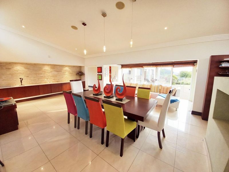 Spacious dining area featuring polished tile floors, a textured stone feature wall with integrated cabinetry, and large sliding doors leading to the outdoor patio.
