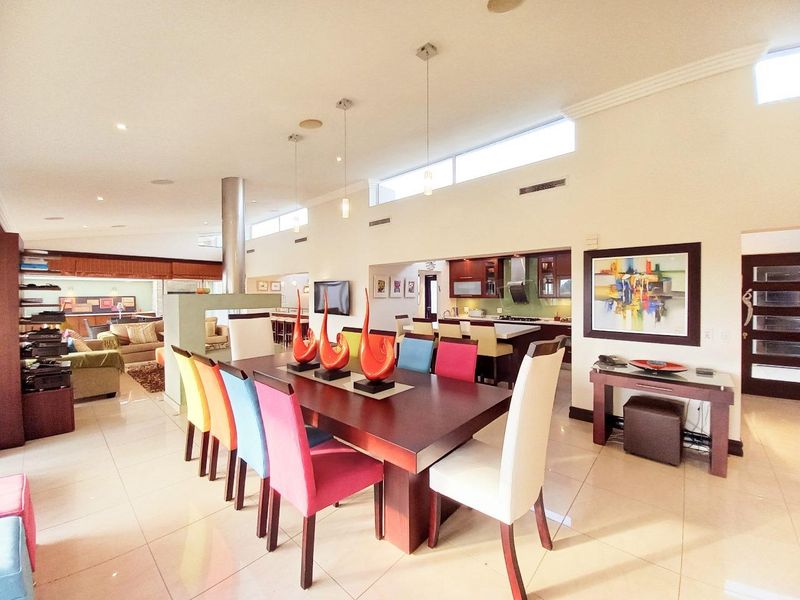 Spacious open-plan living and dining area featuring tiled floors, high ceilings with clerestory windows, and a modern kitchen with integrated cabinetry and island.
