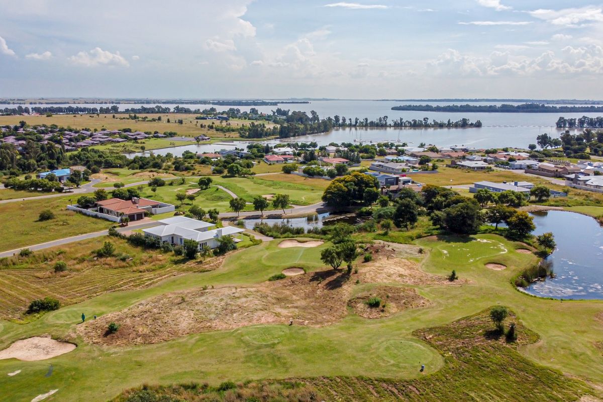 Aerial view of a residential estate situated on a golf course with scenic lake views.