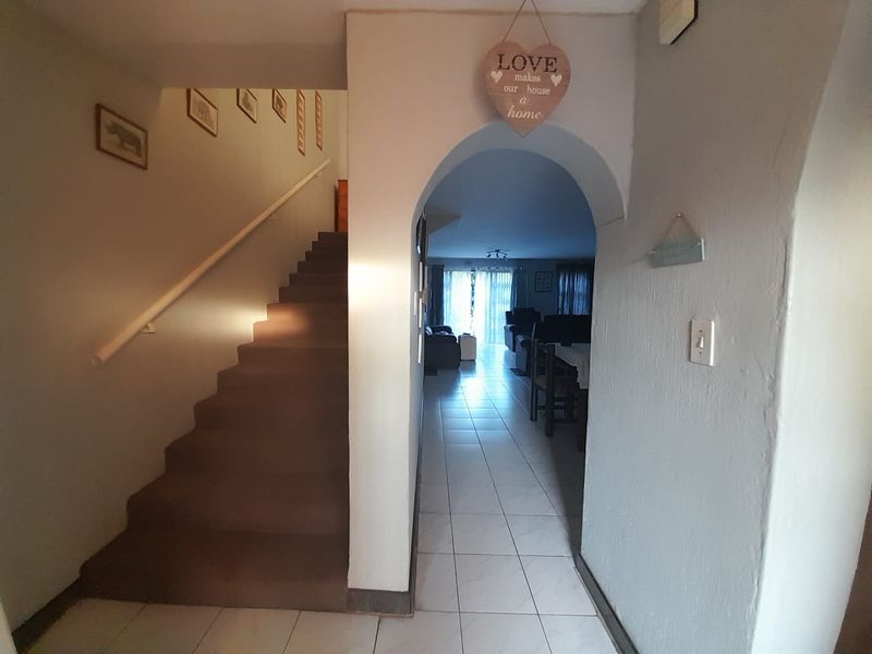 Entrance hallway featuring a staircase with a handrail and an arched entryway leading into the main living area with tiled flooring.