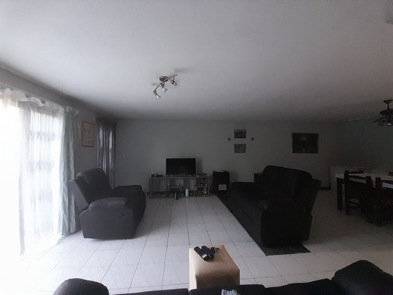 Spacious open-plan living area featuring neutral tiled flooring and large sliding glass doors providing natural light access.