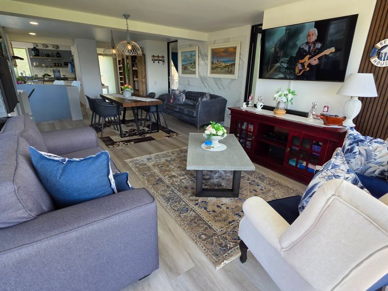Spacious open-plan living and dining area featuring modern laminate flooring, stylish pendant lighting, and a contemporary slatted wood feature wall.