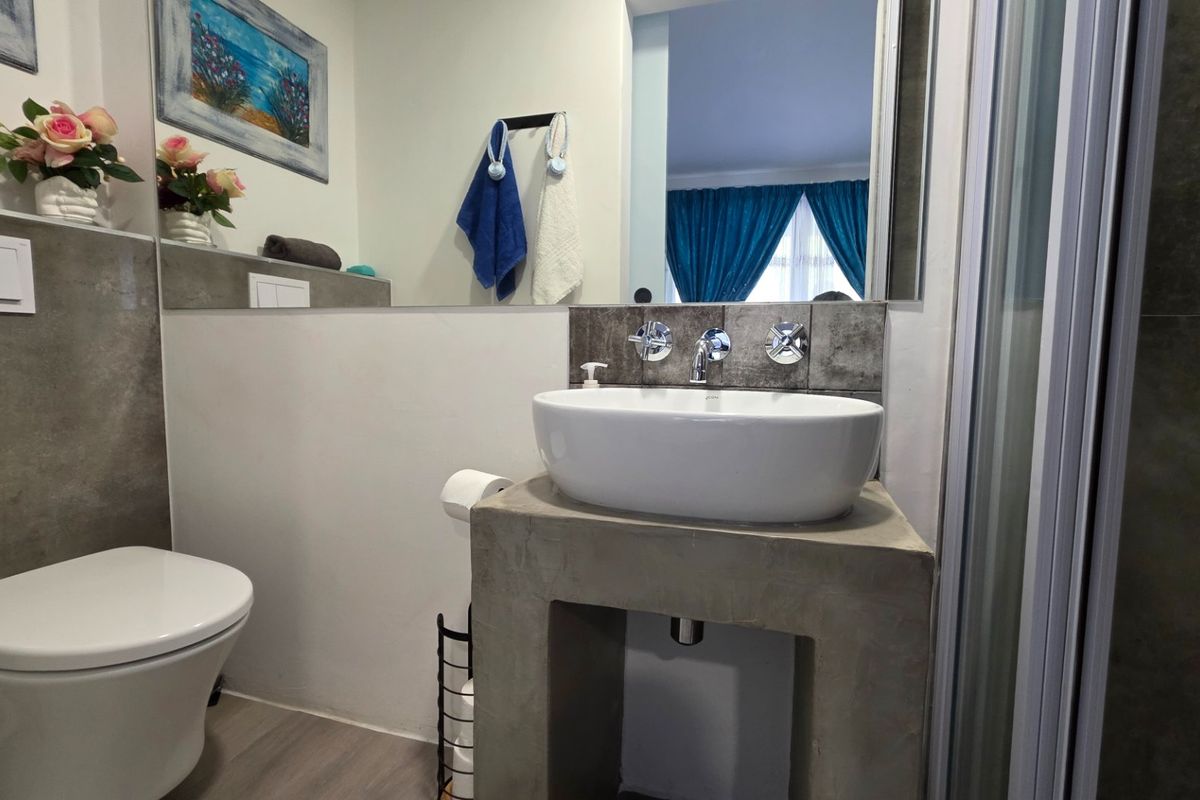 Modern bathroom featuring a wall-mounted toilet, a unique concrete vanity base with a vessel sink, and a sleek shower enclosure.