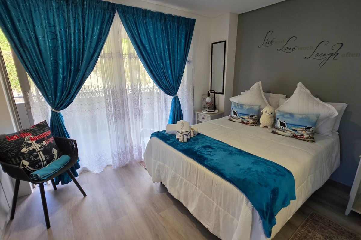 A well-maintained bedroom featuring light laminate flooring, a built-in cupboard, and a sliding glass door providing access to an outdoor area.