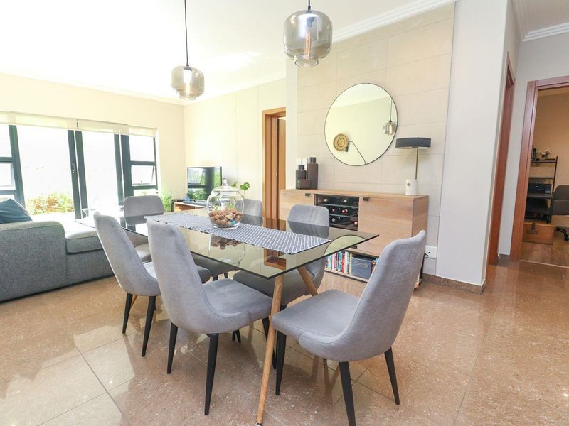 A bright open-plan living and dining area featuring polished tiled flooring, modern pendant lighting, and large sliding glass doors leading to the exterior.