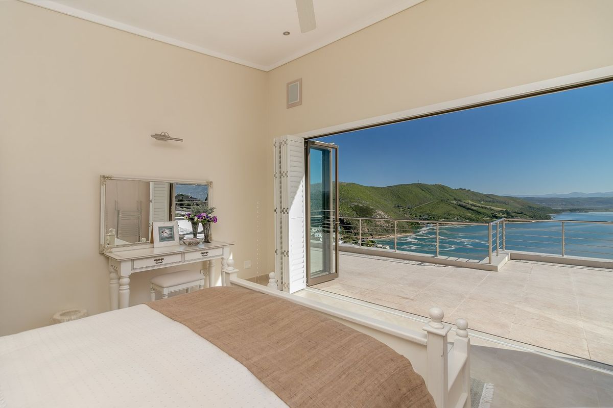 Spacious bedroom featuring large bi-fold doors opening onto a private balcony with expansive coastal and mountain views.