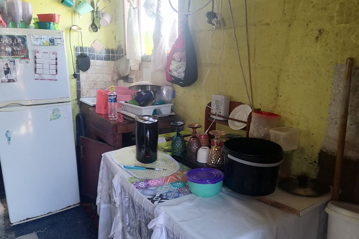 A small kitchen area featuring a sink and tiled splashback, currently requiring significant maintenance and cosmetic updates to the walls and electrical finishes.
