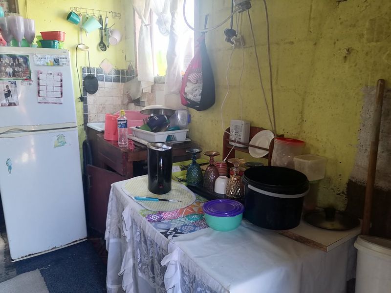 A small kitchen area featuring a sink and tiled splashback, currently requiring significant maintenance and cosmetic updates to the walls and electrical finishes.