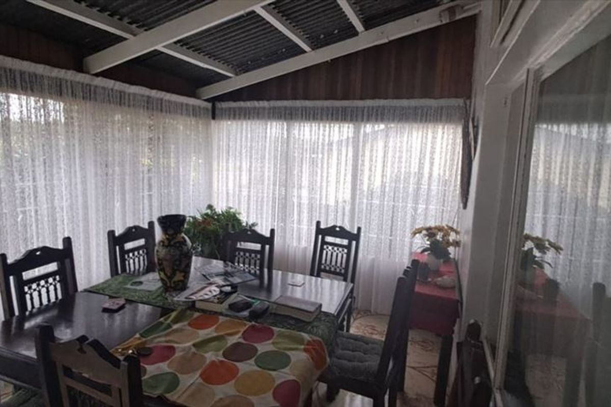 A covered patio area featuring large windows, providing a bright and versatile space for outdoor dining or relaxation.