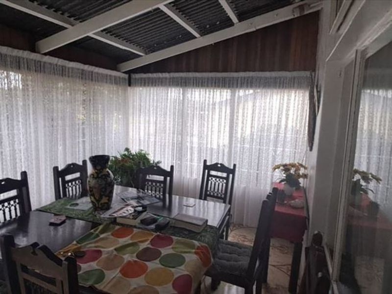 A covered patio area featuring large windows, providing a bright and versatile space for outdoor dining or relaxation.