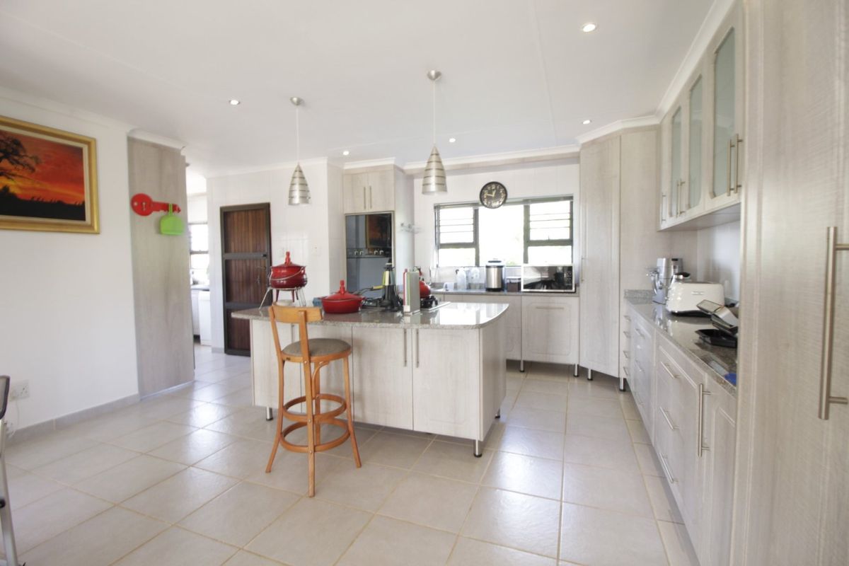 A well-maintained kitchen featuring a central island with granite countertops, ample built-in cabinetry, and modern recessed lighting.