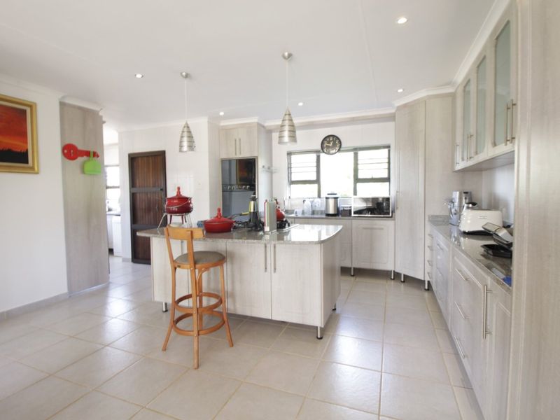 A well-maintained kitchen featuring a central island with granite countertops, ample built-in cabinetry, and modern recessed lighting.