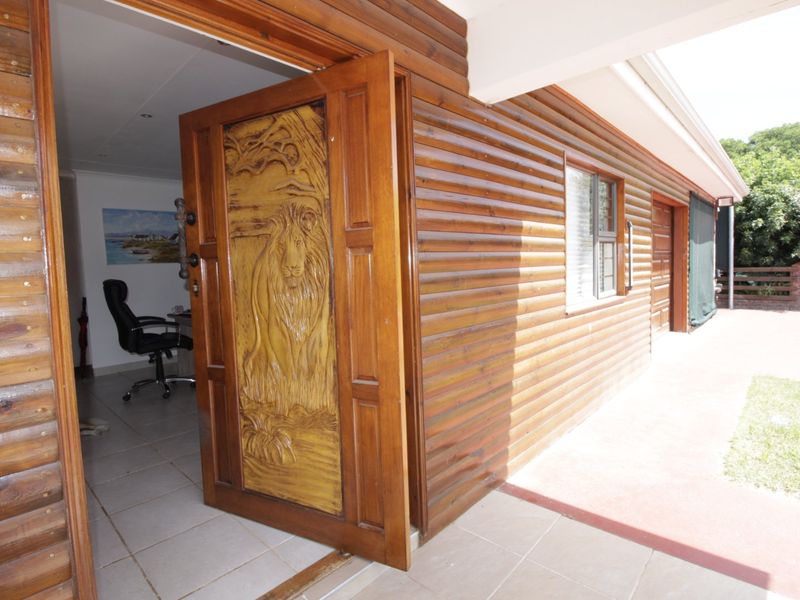 Exterior view of a log cabin style home featuring distinctive carved wooden front door and a covered tiled patio area.