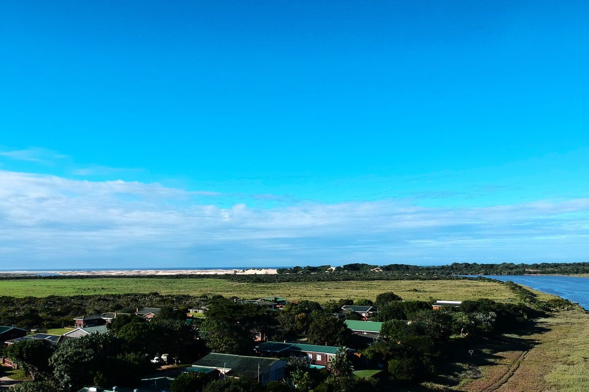 An elevated aerial view showcasing the surrounding coastal landscape, river estuary, and the residential estate setting.