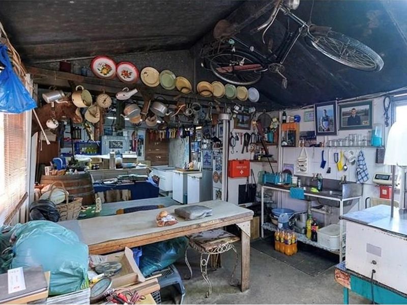 A rustic utility or workshop space featuring exposed timber rafters, a stainless steel sink, and concrete flooring, suitable for farm storage or processing tasks.