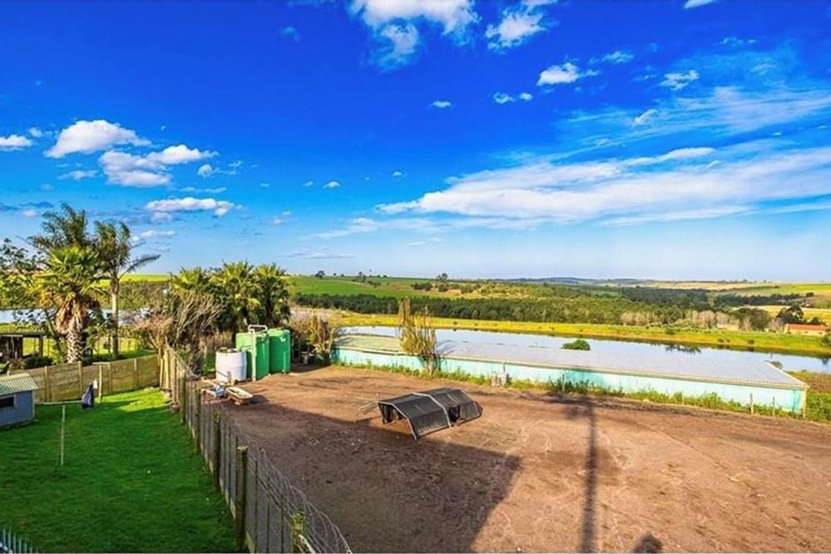 An elevated view of the farm property featuring a large dam, water storage tanks, and fenced outdoor space with rural landscape views.