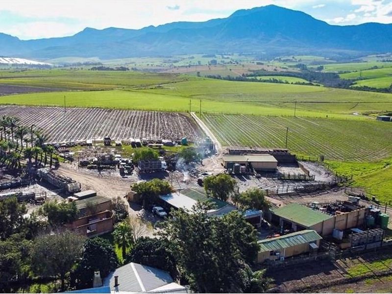 Aerial view of a working farm property featuring multiple outbuildings, agricultural fields, and surrounding rural landscape.