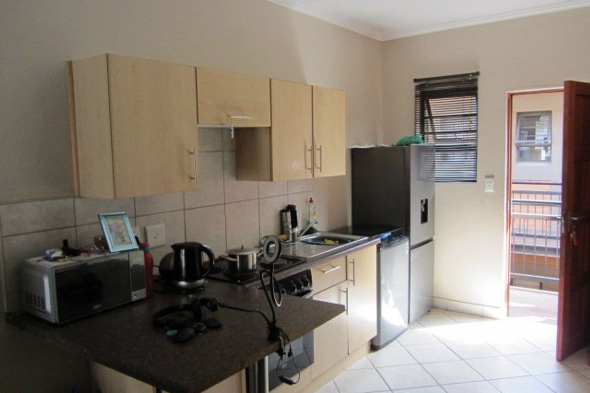 Functional kitchen featuring laminate cabinetry, tiled backsplash, built-in oven, and hob, with direct access to an exterior balcony area.