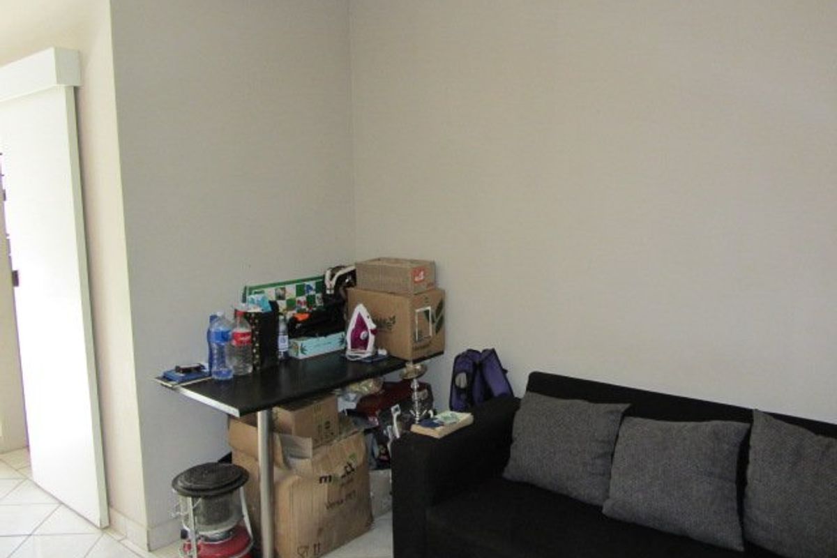 A living room area featuring tiled flooring and a sliding door, currently used as a multi-purpose space.