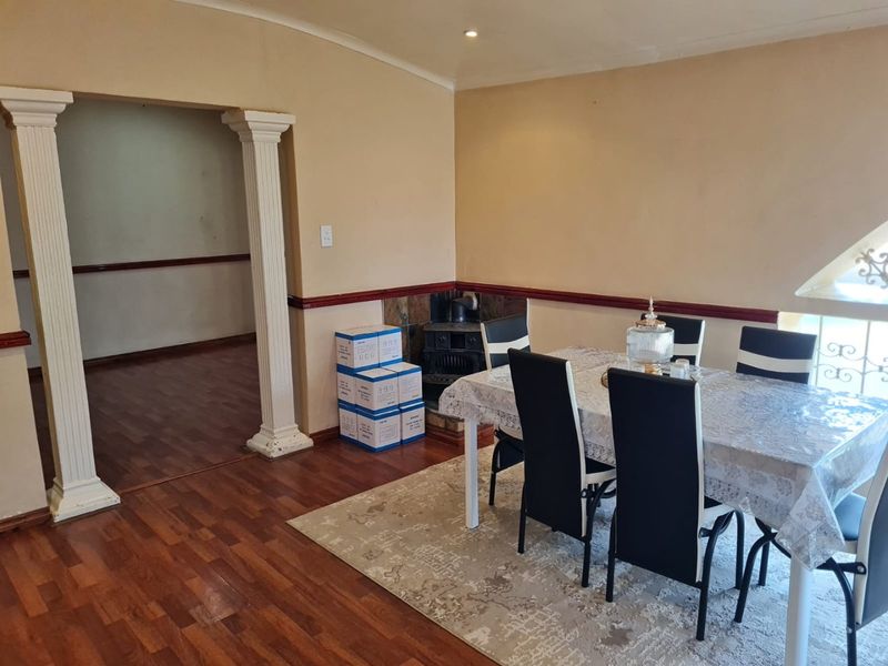 Dining area featuring laminate flooring, decorative columns, and a built-in wood burning stove, providing a functional space for meals.