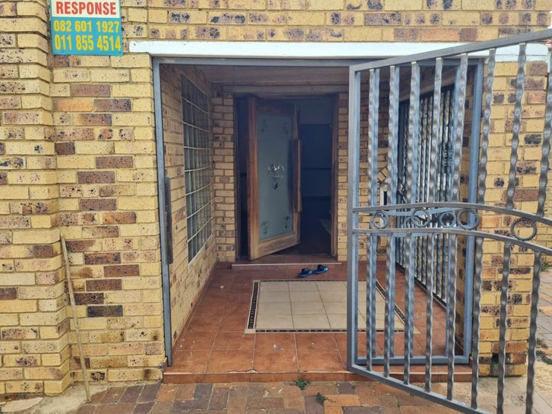 Entrance area featuring a face brick facade, security gate, and tiled porch leading to a timber front door.