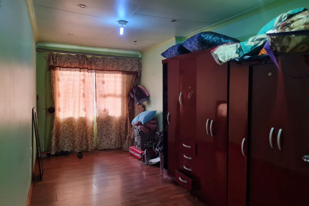 A bedroom featuring laminate flooring and recessed ceiling lighting, currently used for storage with significant wall and ceiling finish wear.