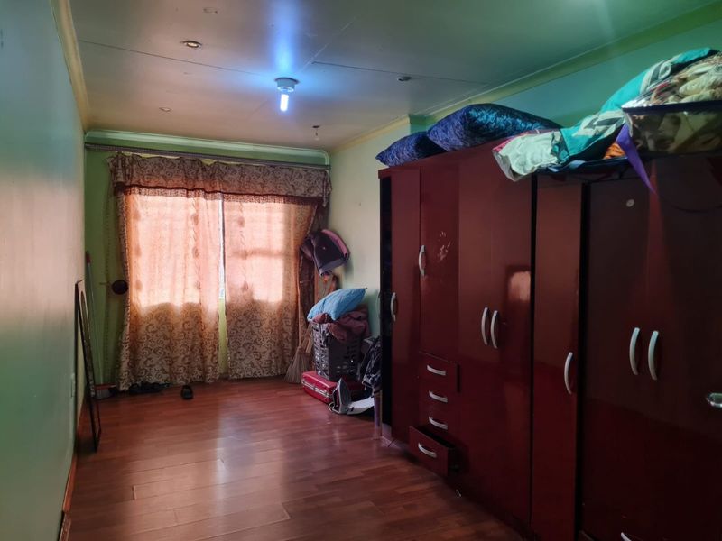 A bedroom featuring laminate flooring and recessed ceiling lighting, currently used for storage with significant wall and ceiling finish wear.