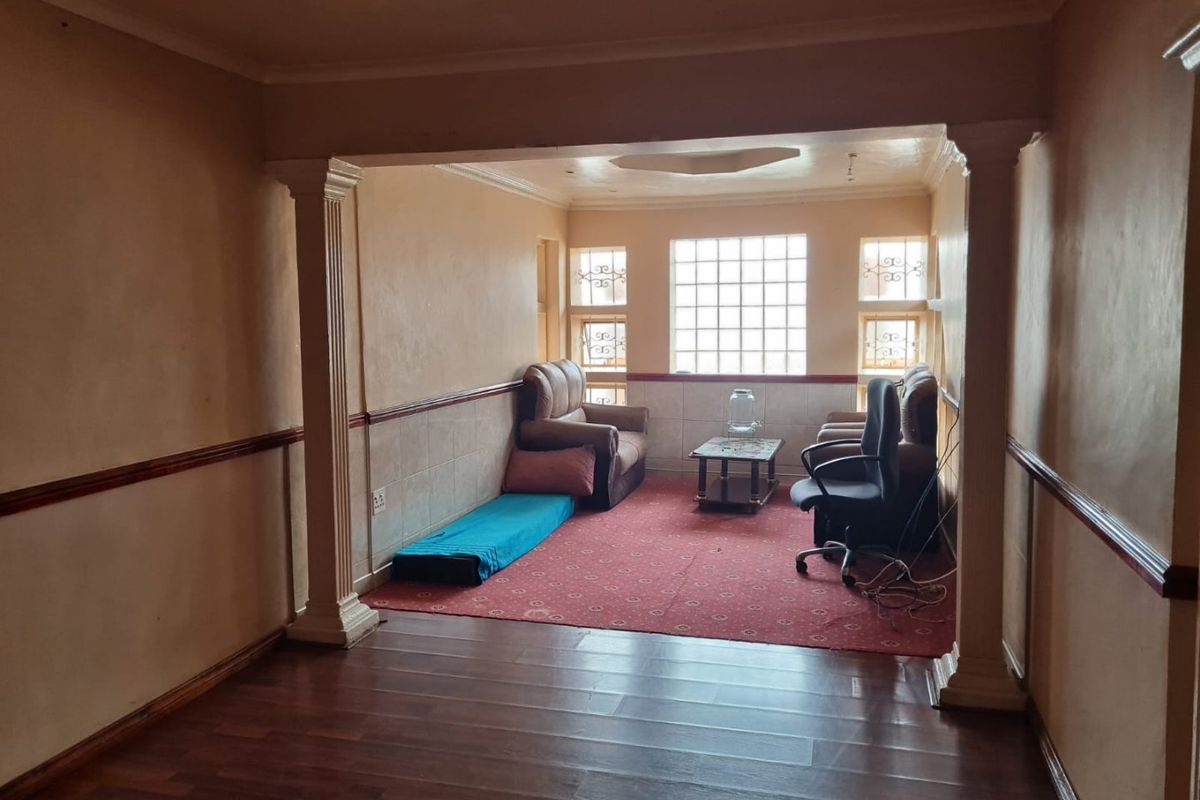 A living area featuring decorative columns, wainscoting, and glass block windows, providing a distinct architectural layout with laminate flooring.