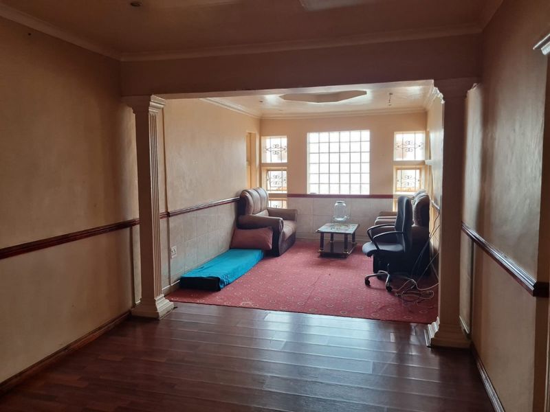 A living area featuring decorative columns, wainscoting, and glass block windows, providing a distinct architectural layout with laminate flooring.
