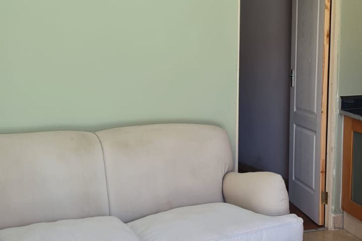 Living room area featuring tiled flooring and light green walls, with an adjacent doorway leading to another room.