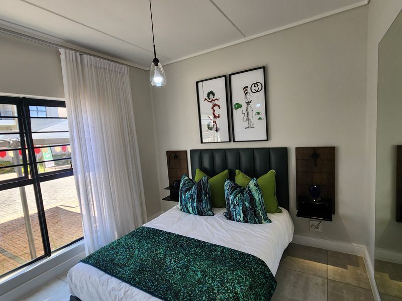 A well-maintained bedroom featuring a built-in headboard, modern pendant lighting, and large windows with curtain tracks, finished with neutral tiled flooring.